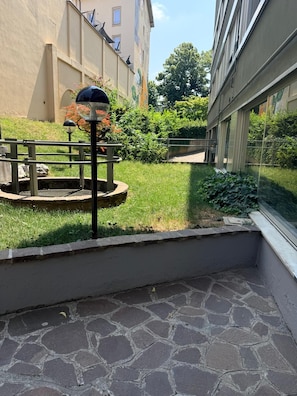 Ein Innenhof mit Steinpflaster, einem Metalllichtpfosten und einer kleinen, runden Gartenanlage.