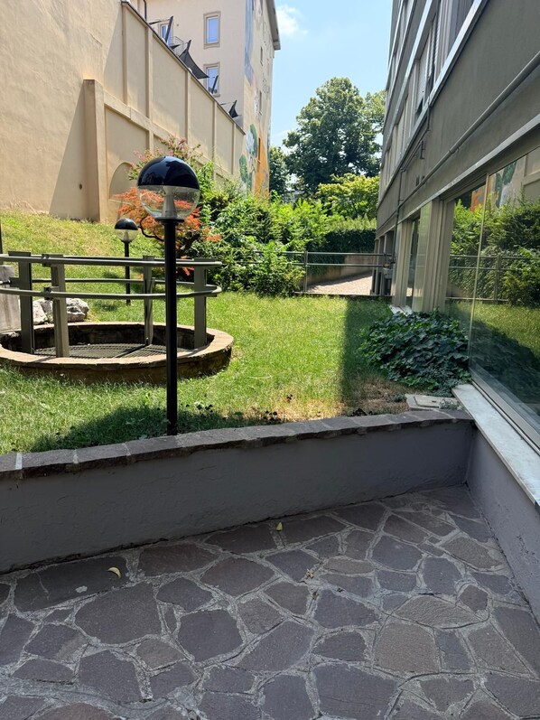 Un patio con piso de piedra, un farol de metal y una pequeña zona de jardín circular.