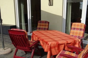An outdoor seating area with a table and chairs, a flag pole, and a building with large windows. - "Little brother"||Schönefeld (Schönefeld)