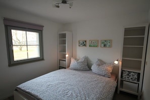 A bedroom with a bed, a window, a built-in wardrobe, and wall art. - Holiday apartment with 1 bedroom (Lohmen)