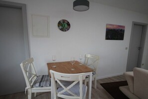 Een eetgedeelte met een houten tafel, twee stoelen en een wandklok.