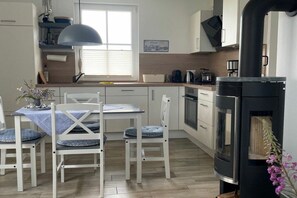 Eine moderne Küche mit Essbereich, einem eingebauten Herd und einem Fenster mit Jalousien.