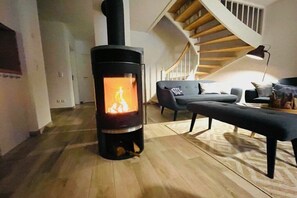 Ein modernes Wohnzimmer mit Kaminofen, Treppe und einer Couch.