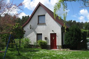 A single-story house with a red door, a small window, and a satellite dish. - Holiday home in Waren with swimming pool (Waren)