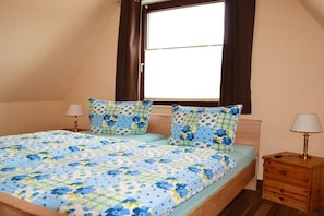 A bedroom with a bed, two bedside tables, a window, and curtains. - Holiday home in Waren with swimming pool (Waren)