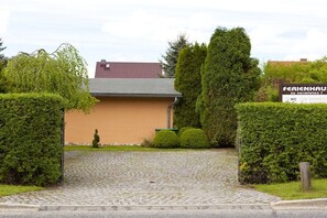 Ein Gebäude mit befestigtem Eingang, umgeben von ordentlich geschnittenen Hecken und einem Schild, das auf ein Geschäft hinweist.