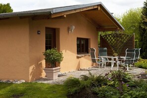 Una casa amb un pati, mobiliari d'exterior i un jardí.