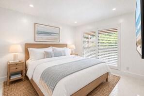 A bedroom with a bed, bedside tables, a window with blinds, and a framed picture on the wall. - Renovated PGA National Home by Guaranteed Rental (Palm Beach Gardens)