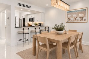 A modern kitchen with white cabinets, stainless steel appliances, and a central island with bar stools. - Renovated PGA National Home by Guaranteed Rental (Palm Beach Gardens)