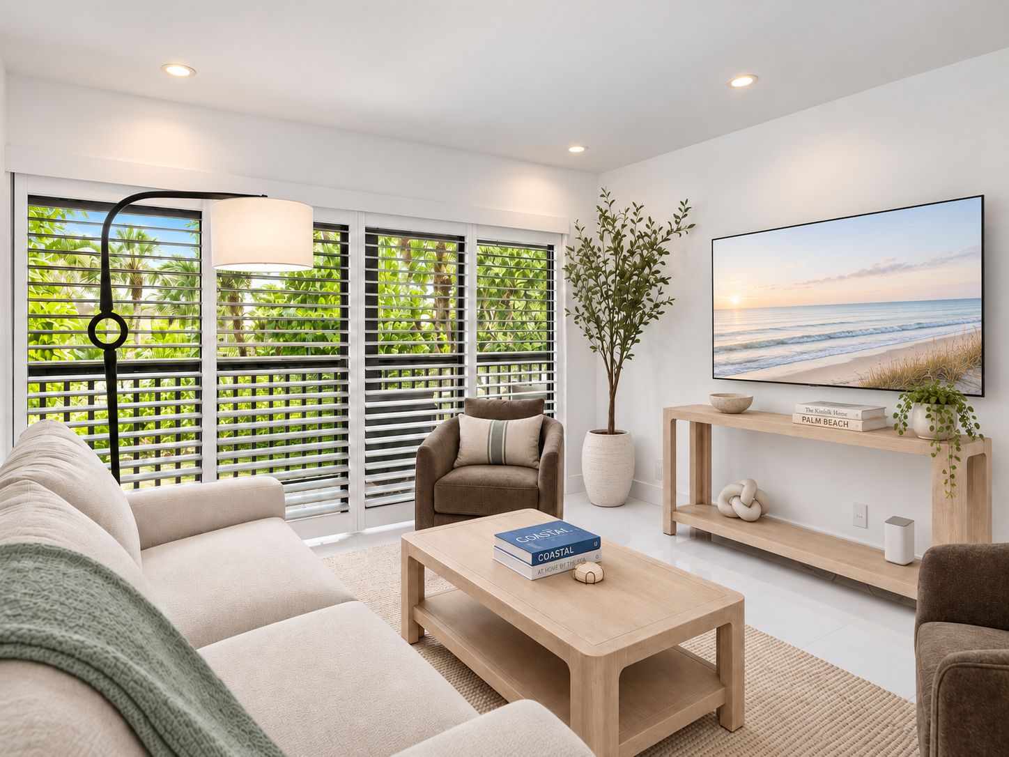 A modern living room with a sofa, coffee table, and a TV on a wall.