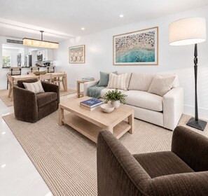 Un salon moderne comprenant un canapé, des fauteuils, une table basse et un coin repas.