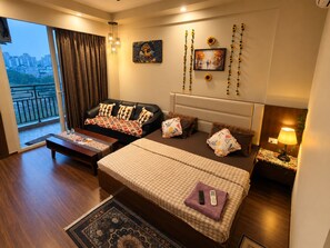 Une chambre d’hôtel avec un grand lit, un canapé, un bureau et un balcon avec vue.