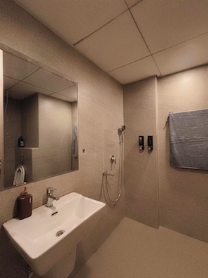 A bathroom with a sink, mirror, shower, and towel rack.
