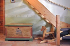 Ein hölzernes Schaukelpferd und eine Kommode in einem Zimmer mit schragem Dach und einer Holztreppe.