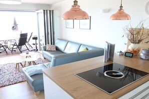 A modern living space with a sofa, a dining area, and a kitchen with a built-in stove. - Holiday home in Waren with swimming pool (Waren)