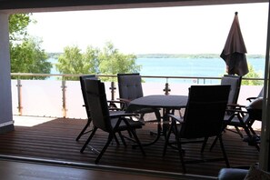 A balcony with a table and chairs overlooking a body of water. - Holiday home in Waren with swimming pool (Waren)