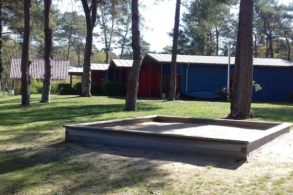 Ein Campingplatz mit mehreren Holzhütten, einem Picknicktisch und einer von Bäumen umgebenen Rasenfläche.