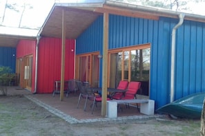 Ein Gebäude mit einer überdachten Terrasse, einem Tisch mit Stühlen und einem in der Nähe stehenden Auto.