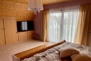 A bedroom with a bed, a television, wooden cabinets, and a window with curtains. - Crane in Röbel/Müritz (Röbel\/Müritz)