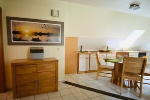 A dining area with a table and chairs, a wooden cabinet, and a painting on the wall. - Crane in Röbel/Müritz (Röbel\/Müritz)