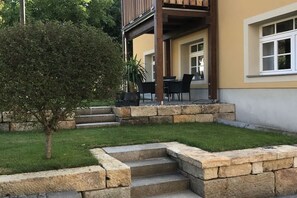 A residential property with a stone staircase leading to a wooden deck, a small tree, and a well-maintained lawn. - in the Schumannhof at the Lotzbach Cossebaude (Dresden)
