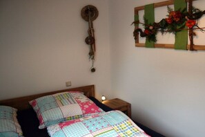 A bedroom with a bed, a nightstand, a wall clock, and a wall decoration. - Holiday apartment with 1 bedroom (Lübben \/ Spreewald)