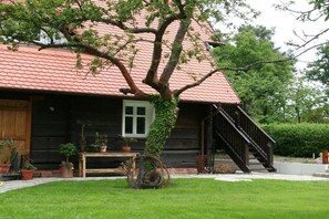 A wooden house with a red-tiled roof, a wooden staircase, and a small garden area with potted plants. - Holiday apartment with 1 bedroom (Lübben \/ Spreewald)