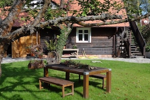 A rustic wooden house with a red-tiled roof, a wooden bench, and a table in the foreground. - Holiday apartment with 1 bedroom (Lübben \/ Spreewald)