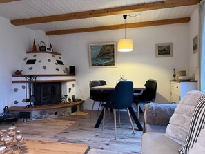 A cozy room with a fireplace, dining table, chairs, and a sofa. - House Strandherz House Section Starboard (Utersum)