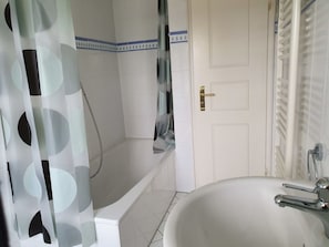 Ein Badezimmer mit einer Badewanne, einer Duschvorhang und einem Waschbecken mit Wasserhahn.