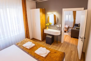 Ein Hotelzimmer mit Bett, einem Badezimmer mit Spiegel und Waschbecken sowie einer Wohnbereich mit Sofa und Tisch.