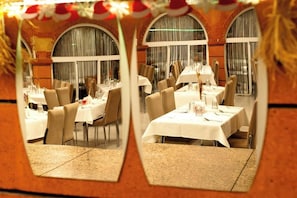 Ein Restaurant mit gedeckten Tischen, großen Bogenfenstern und einer Backsteinwand.