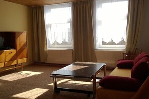 A living room with a sofa, a television on a wooden cabinet, and a table. - Holiday apartment with 1 bedroom (Zehdenick)