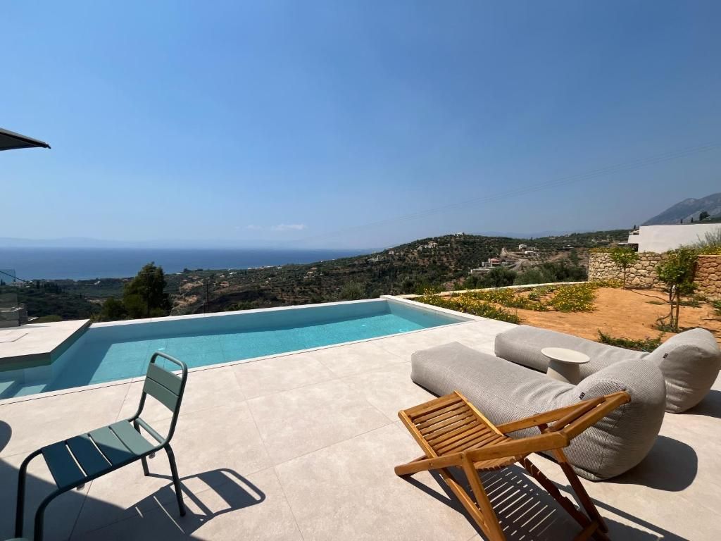 Un espace piscine avec vue sur la mer, comprenant un fauteuil de relaxation et un canapé.