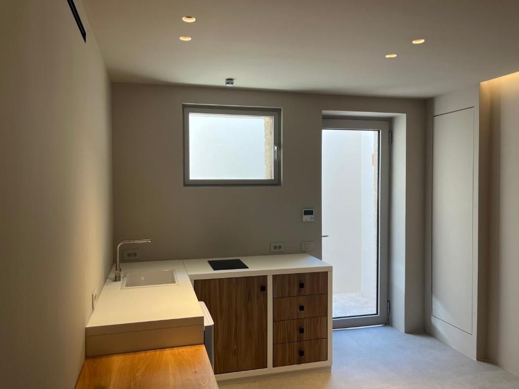 A modern bathroom with a large window, a built-in sink, and a wooden cabinet.