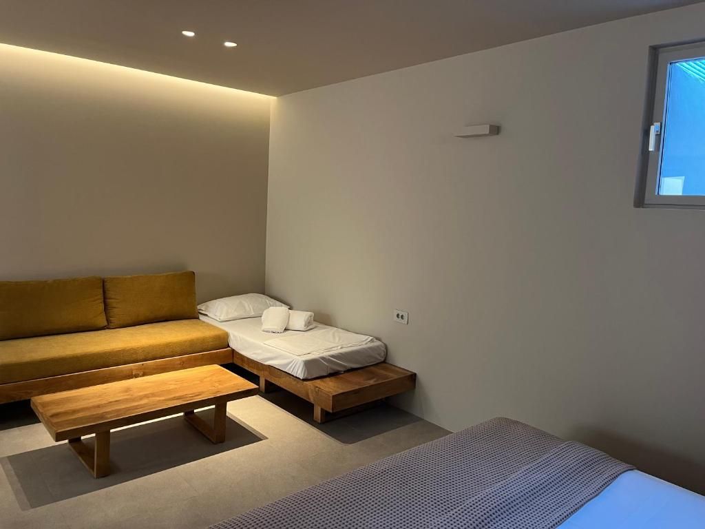 A modern room with a sofa, a bed, a bench, and a window.