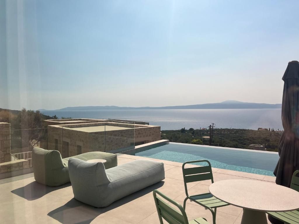 Eine Dachterrasse mit Swimmingpool, Sitzgelegenheit und Meerblick.