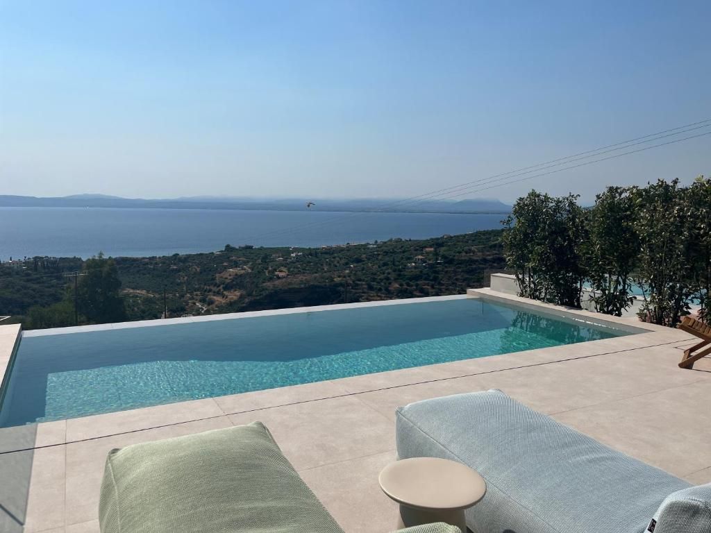 A clear view of a swimming pool with lounge chairs and a view of the sea.