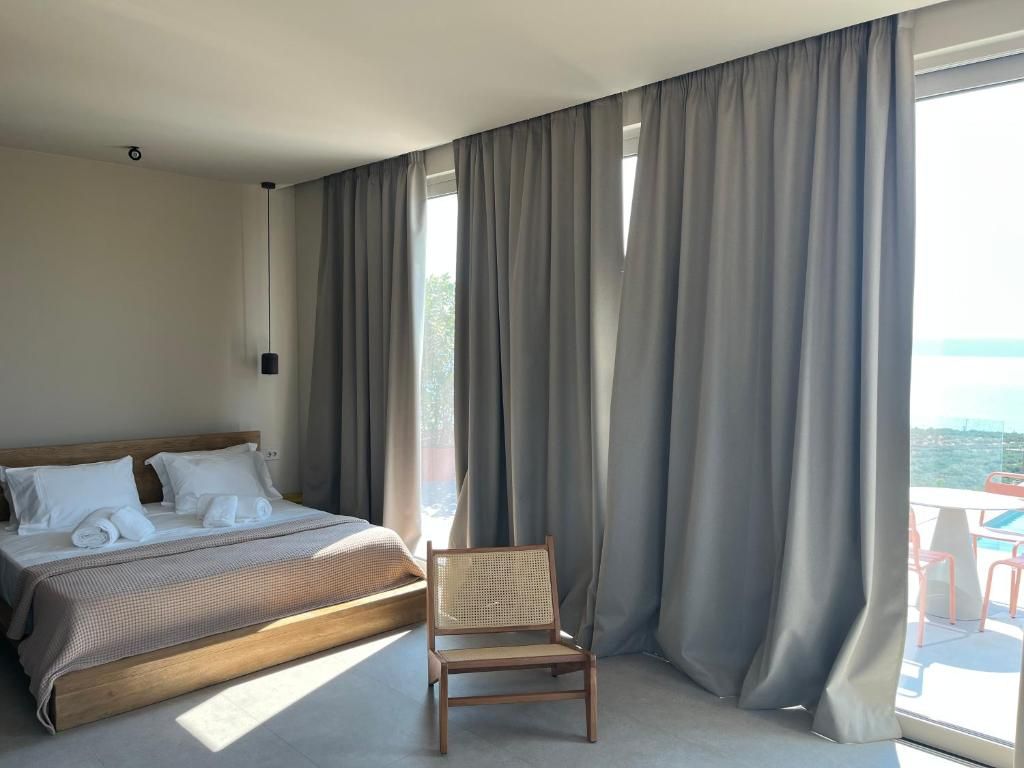 A bedroom with a bed, a chair, and a view of the outdoors.