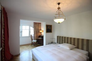Ein Hotelzimmer mit Bett, Schreibtisch, Stuhl und Fenster.