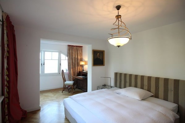 A hotel room with a bed, a desk, a chair, and a window.