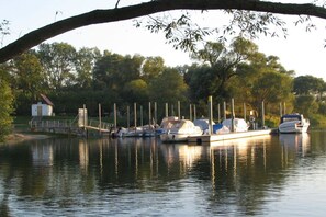 A calm lake with boats docked at a pier, surrounded by trees. - Apartment Sternenblick (Havelaue)