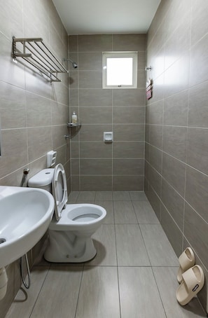 Un bagno moderno con WC, bidet e lavandino. Si nota una finestra e un portasciuga sulla parete.