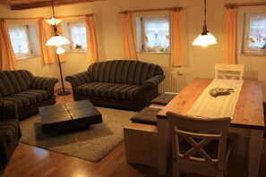 A cozy living room with striped sofas, a wooden coffee table, and a dining table with chairs. - Holiday home in spa town Jonsdorf with sauna (Kurort Jonsdorf)