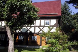 A traditional half-timbered house with a red roof, surrounded by greenery. - Holiday home in spa town Jonsdorf with sauna (Kurort Jonsdorf)