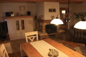 Een gezellige woonkamer met een open haard, houten meubels en een eettafel.