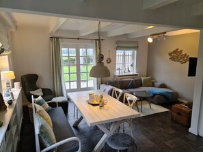 A cozy living room with a dining table, a sofa, and a chair. There is a window with curtains, a lamp, and a small table with a lamp. - Holiday Home in Wrixum With Terrace (Wrixum)