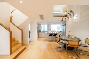 A modern kitchen with wooden flooring, a dining area with a table and chairs, and a staircase. - Book&Bed-The Bund People's Square 1 (Shanghai)