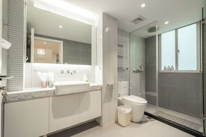A modern bathroom with a large mirror, a sink, a toilet, and a glass-enclosed shower. - Book&Bed-The Bund People's Square 1 (Shanghai)