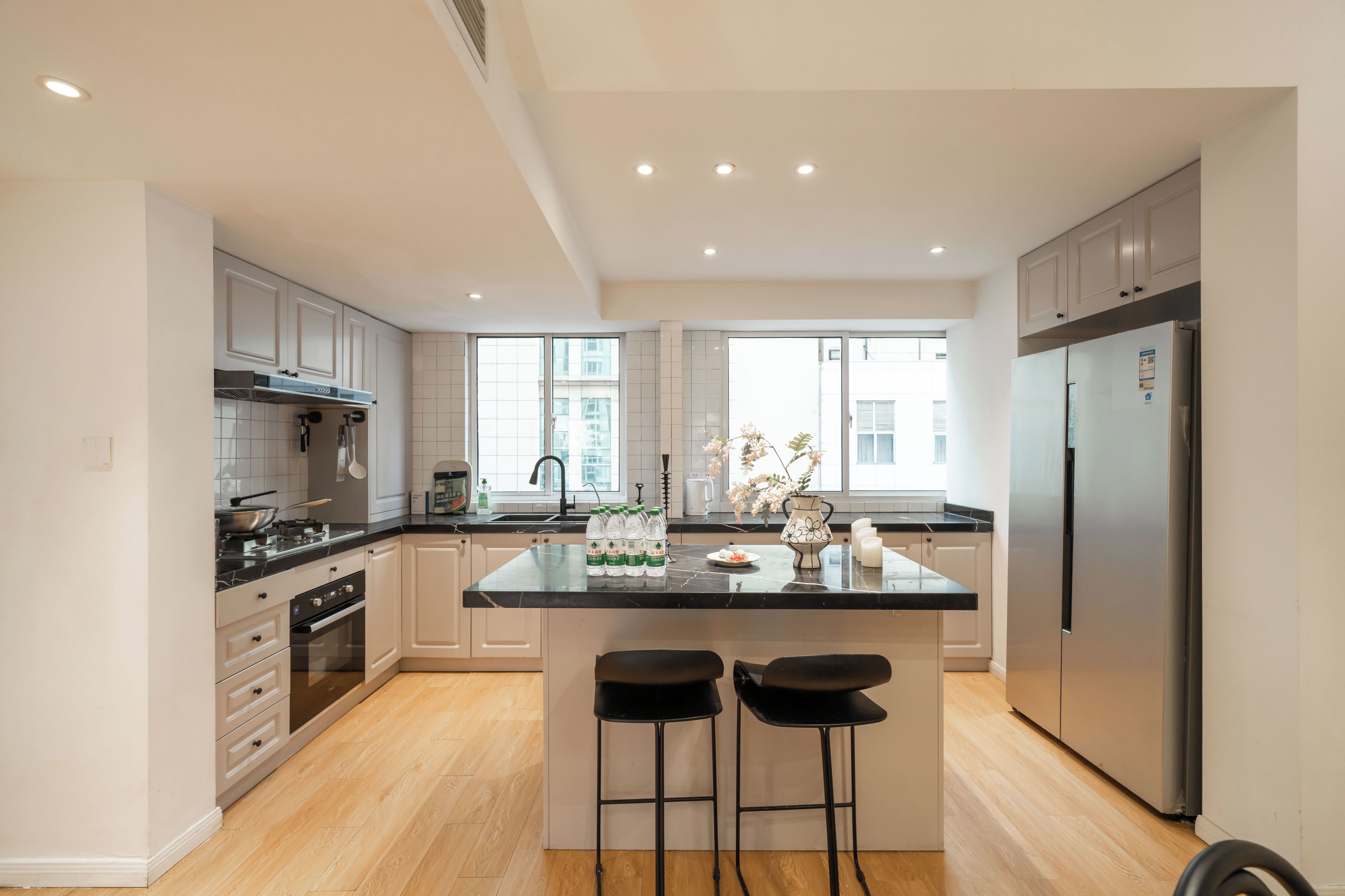 A modern kitchen with a central island, stainless steel appliances, and a view to the outside.